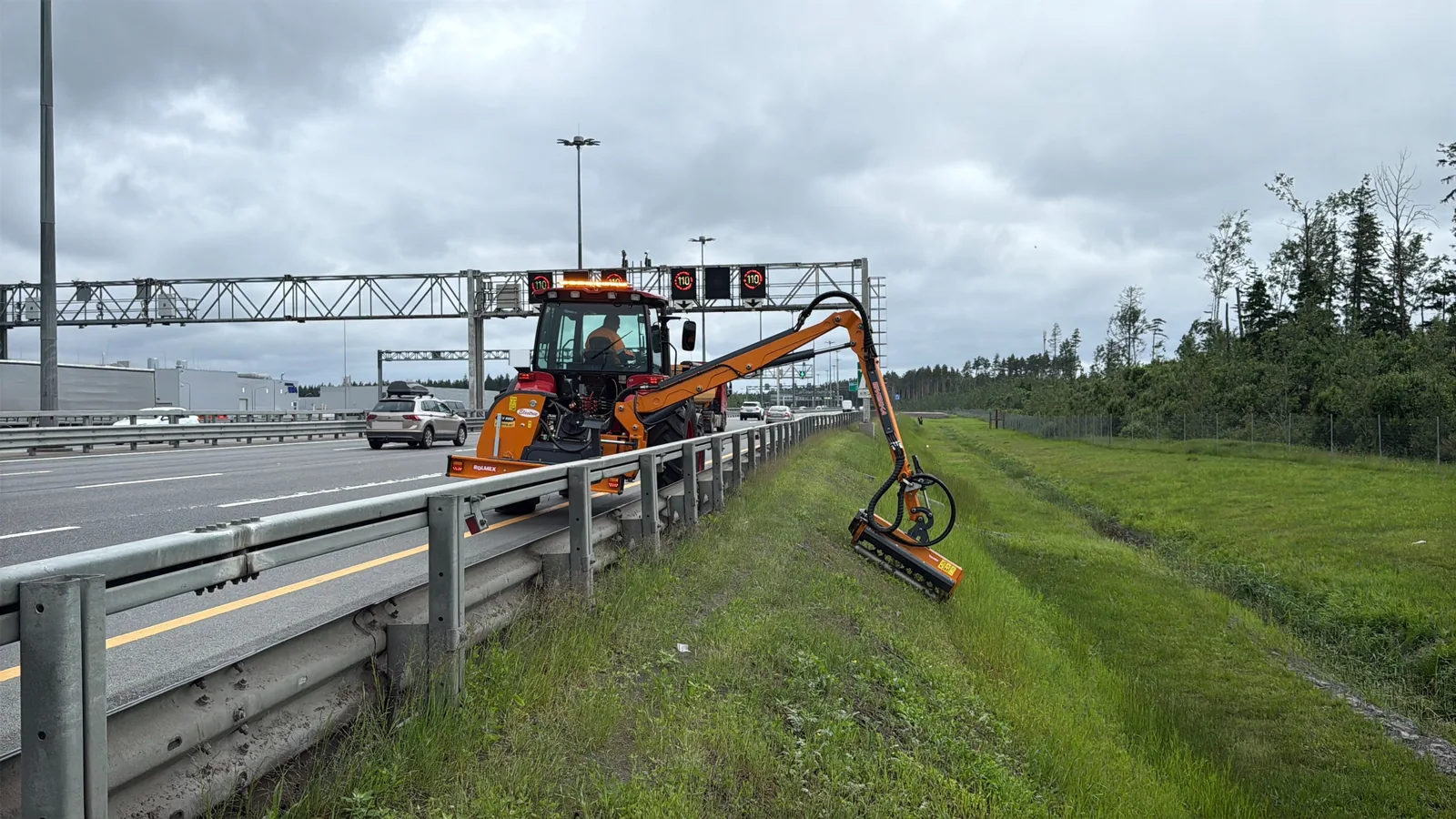 Kosiarka wysięgnikowa Rolmex w pracy na poboczu drogi ekspresowej — ramię hydrauliczne z głowicą bijakową kosi trawę za barierą ochronną
